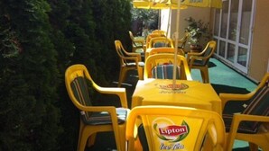 An outdoor seating area with yellow chairs and tables, each with a Lipton Ice Tea logo.