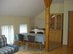 Un espacio habitable compacto con comedor, kitchenette y un armario de madera.
