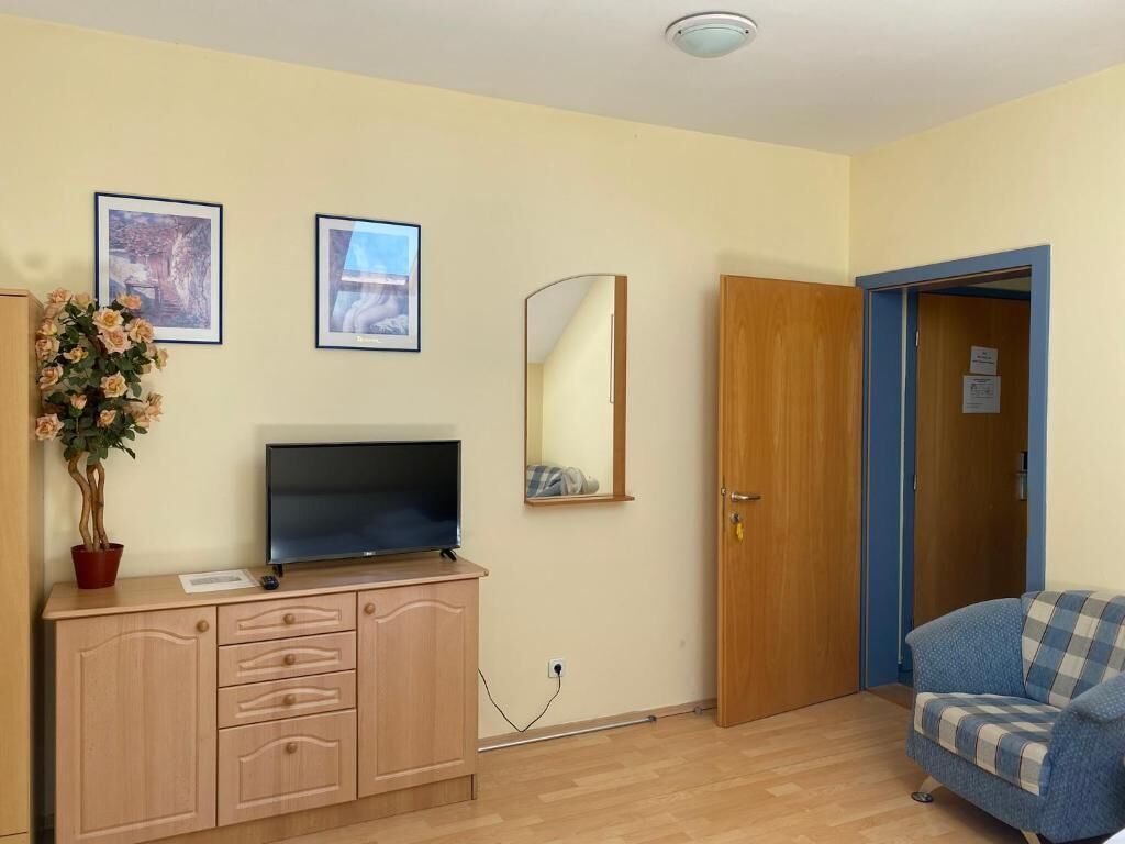 A room with a television on a wooden cabinet, a mirror, a door, and a blue sofa.
