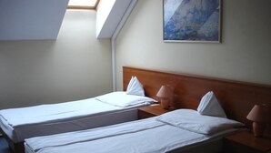 A hotel room with two single beds, a wooden headboard, bedside lamps, and a skylight.