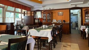 A dining area with multiple tables, chairs, and a kitchen in the background.