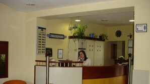 Een receptie met een receptionist, een receptiebalie, een informatiemap en een bordje dat de locatie van het toilet aangeeft.