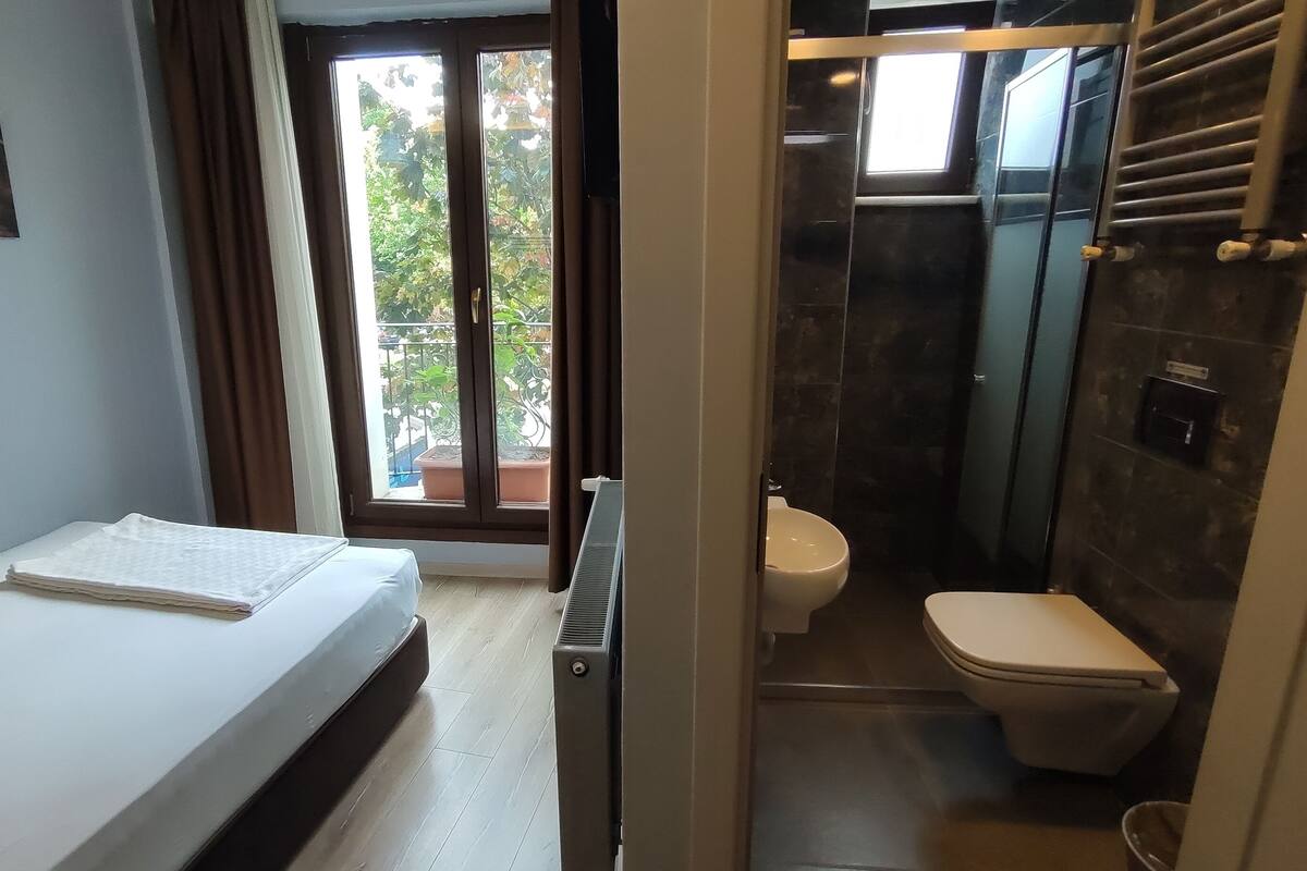 Ein Schlafzimmer mit einem Bett, einer Heizung und Blick auf einen Balkon mit Pflanzen.