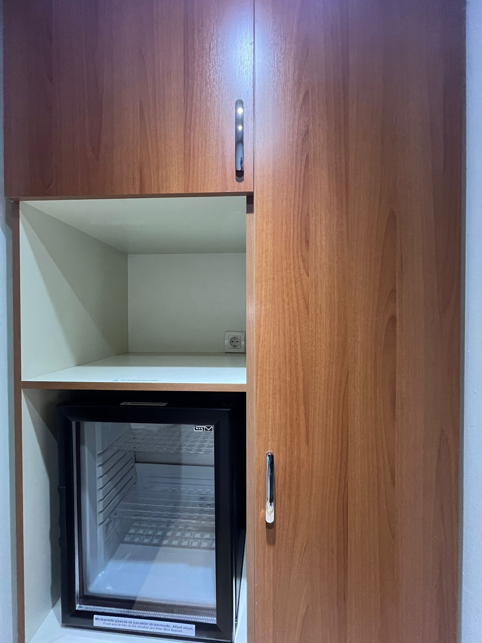 Un mueble de madera con un mini refrigerador incorporado y un estante.