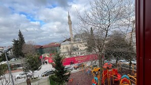 A playground with various play equipment, a mosque with a minaret in the background, and a pedestrian walkway. - Hotel Torun Istanbul Old City (Istanbul)