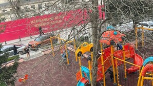 A playground with slides and climbing structures, surrounded by a red fence and a tree. - Hotel Torun Istanbul Old City (Istanbul)