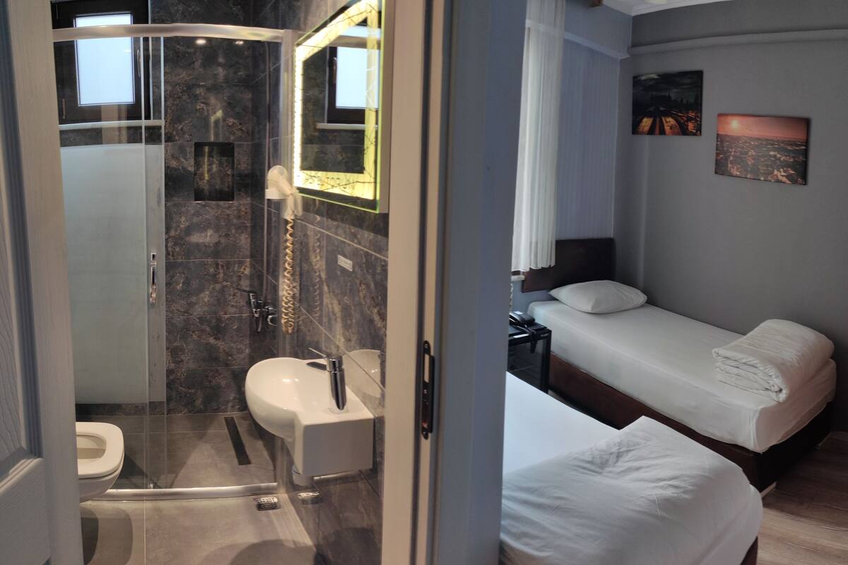 Ein Hotelzimmer mit Dusche, WC und einem Bett mit Nachttisch.