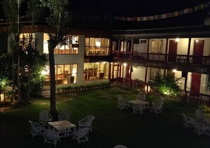 A two-story building with multiple windows and balconies, surrounded by a well-lit outdoor area with chairs and tables. - Hotel Shambhala Resort (Leh)