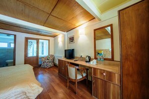 A bedroom with a bed, a desk with a TV, a chair, a mirror, and a window. - Hotel Shambhala Resort (Leh)
