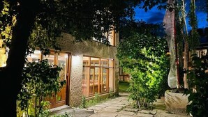 Une maison avec une façade en pierre, une porte en verre et un chemin en pierre menant à l’entrée.