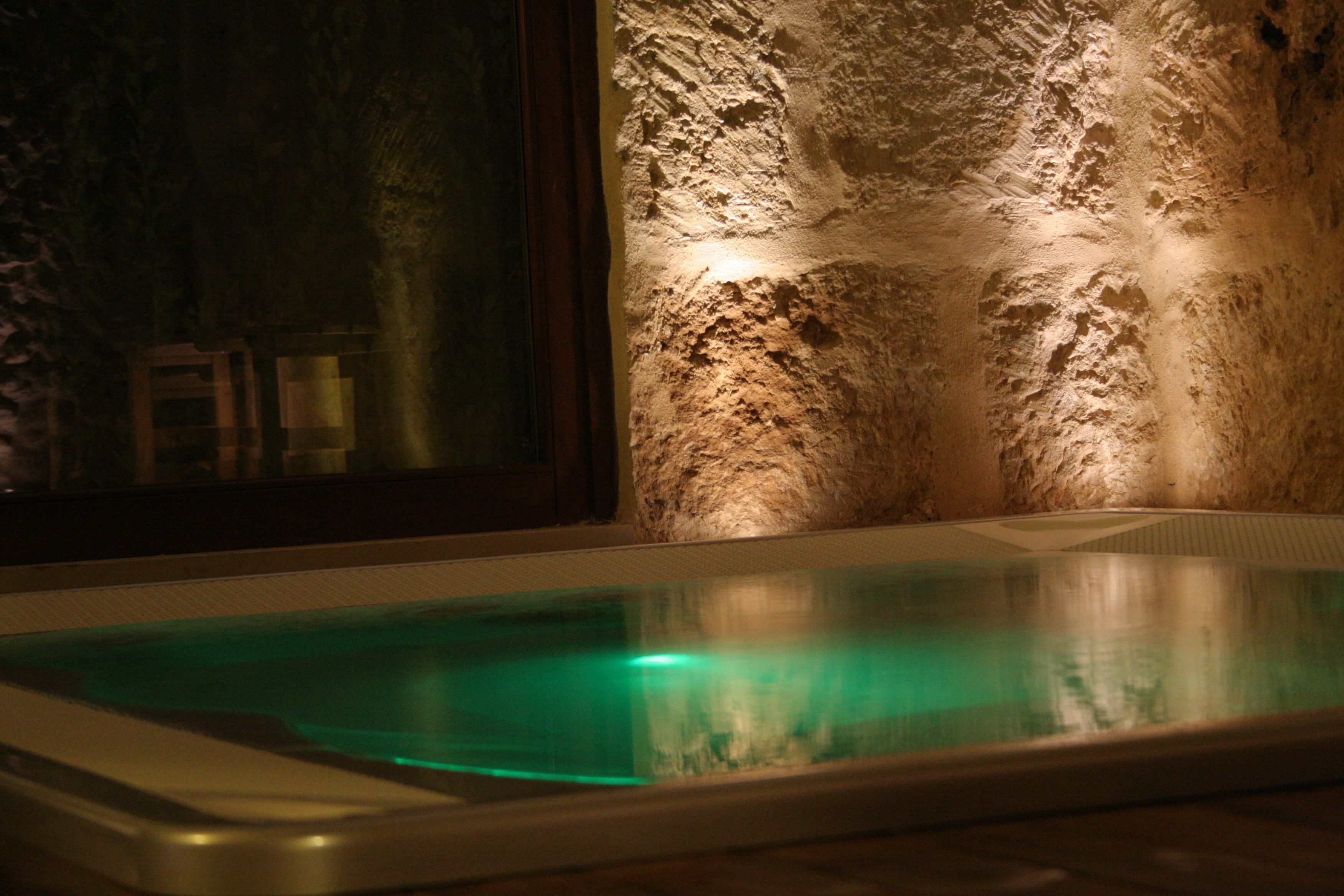 Un'area benessere con parete in pietra e vasca idromassaggio vetrata.