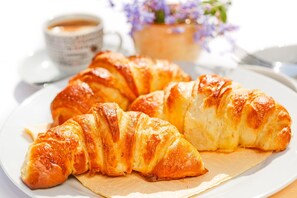 Un plato de croissants sobre un plato blanco, con una taza de café al fondo.