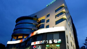 A modern hotel with a curved facade, multiple floors, and illuminated signage. - Capitol Hill (Ranchi)