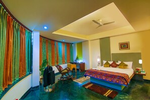 A hotel room with a bed, desk, chair, and curtains. - Capitol Hill (Ranchi)