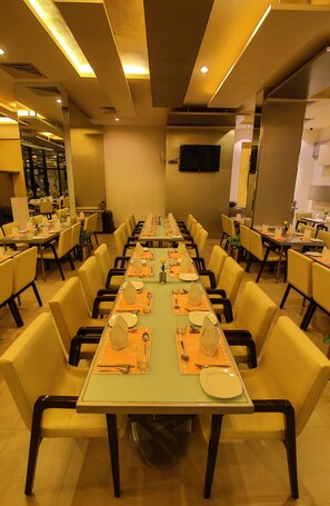 A conference room with multiple tables set for dining, equipped with chairs and table settings. - Capitol Hill (Ranchi)