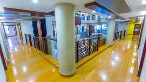 A spacious, multi-level corridor with polished wooden floors, large columns, and a modern railing design. - Capitol Hill (Ranchi)