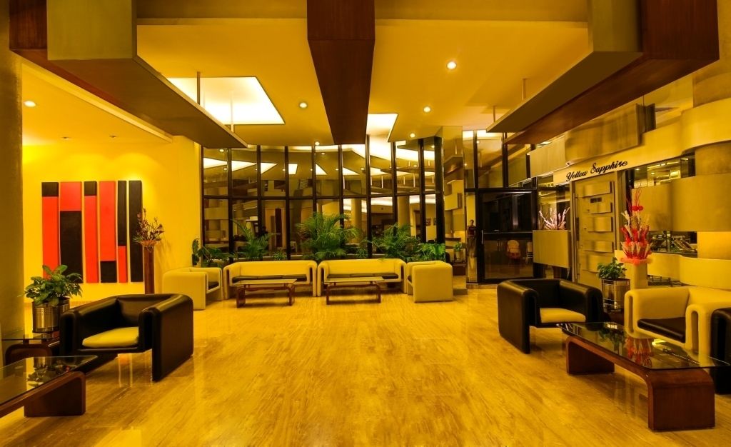 A modern lobby with a wooden floor, yellow sofas, and a reception desk.