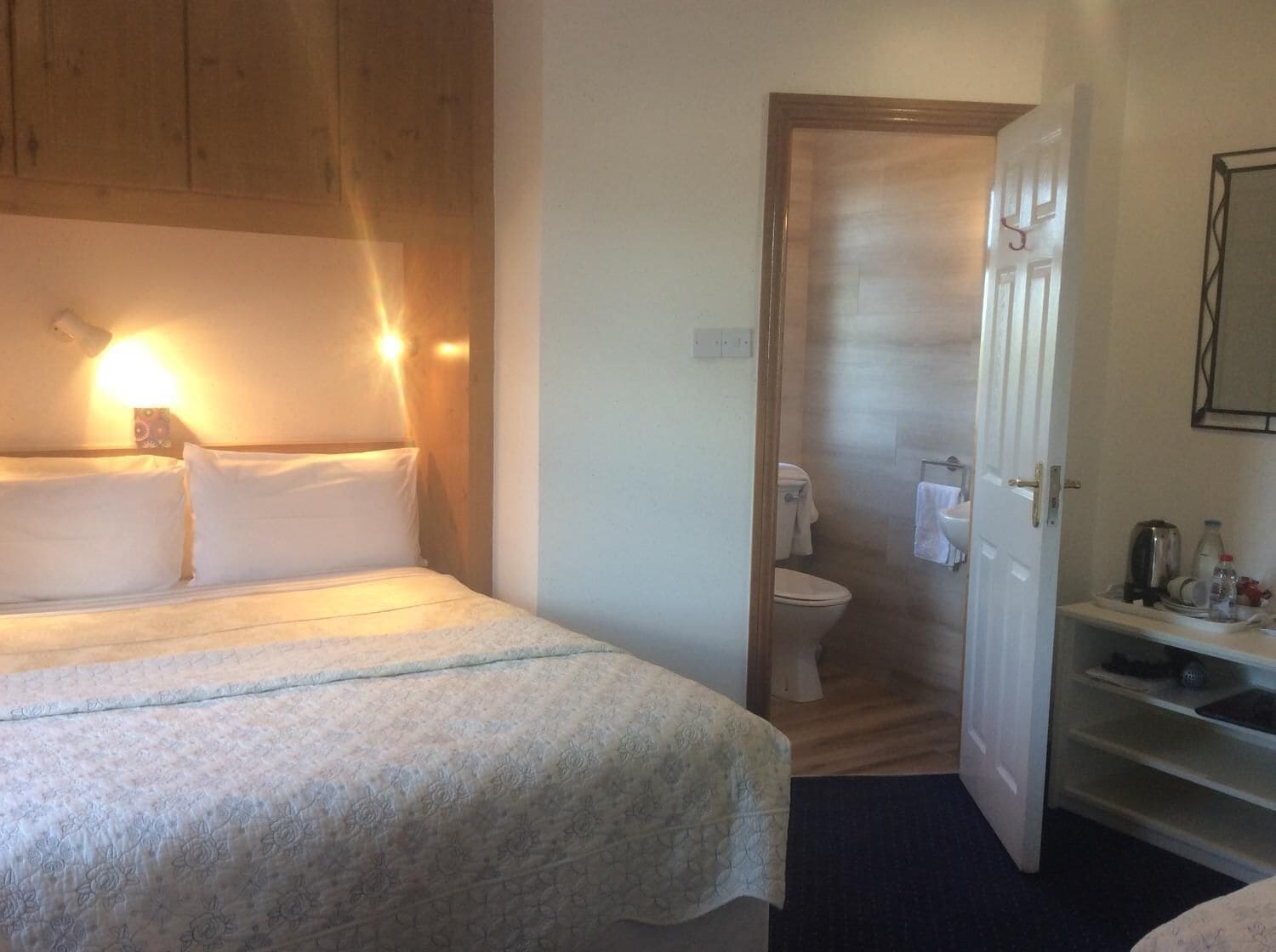 Un dormitorio con una cama, una lámpara de noche y un cabecero de madera.