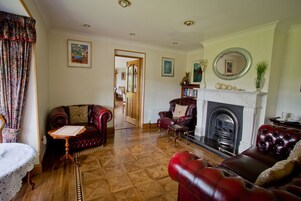 Una sala de estar tradicional con chimenea, sofás de cuero y un área de comedor visible a través de una puerta abierta.