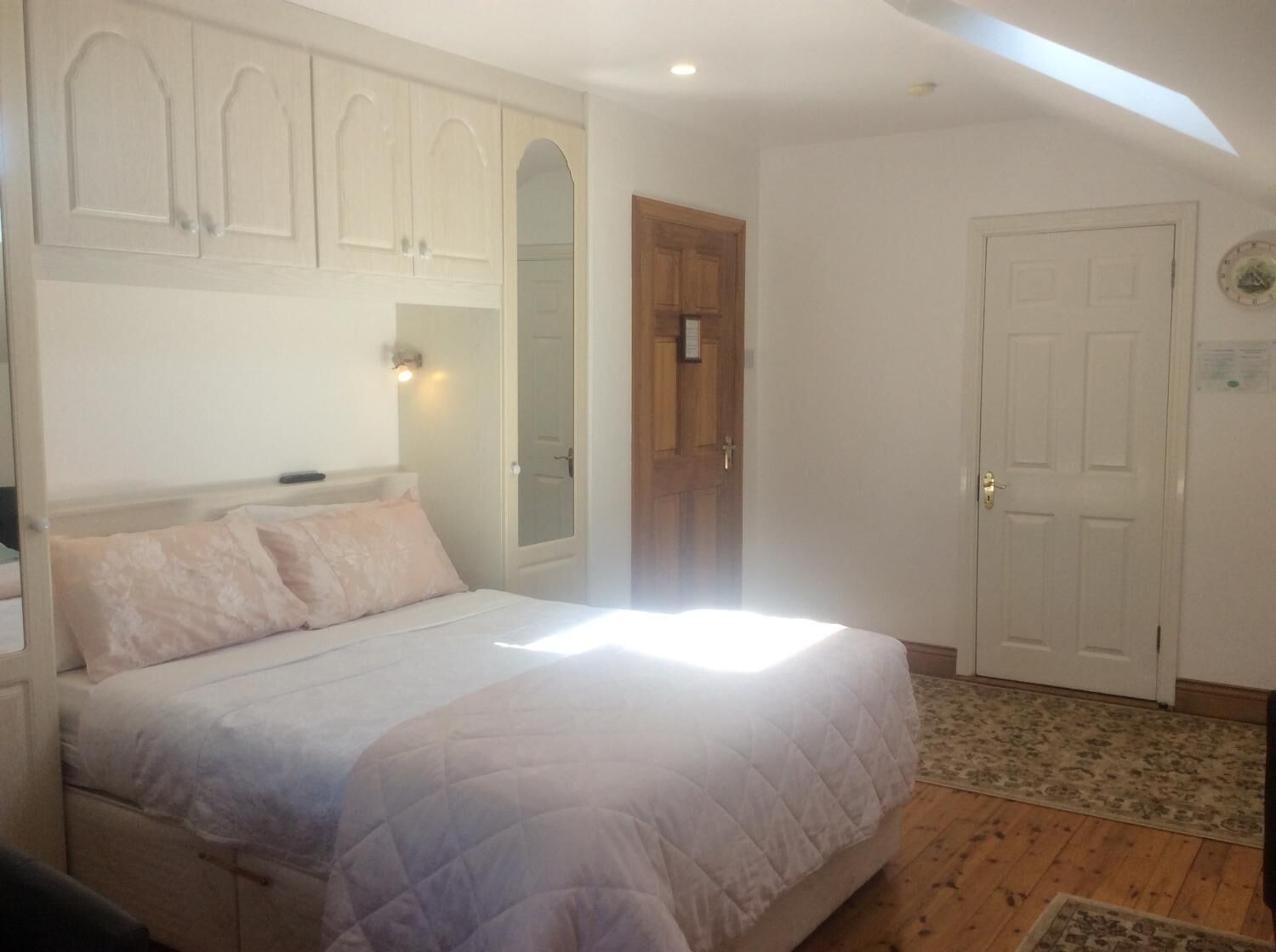 Ein Schlafzimmer mit Bett, Kleiderschrank, Tür und einem kleinen Teppich.