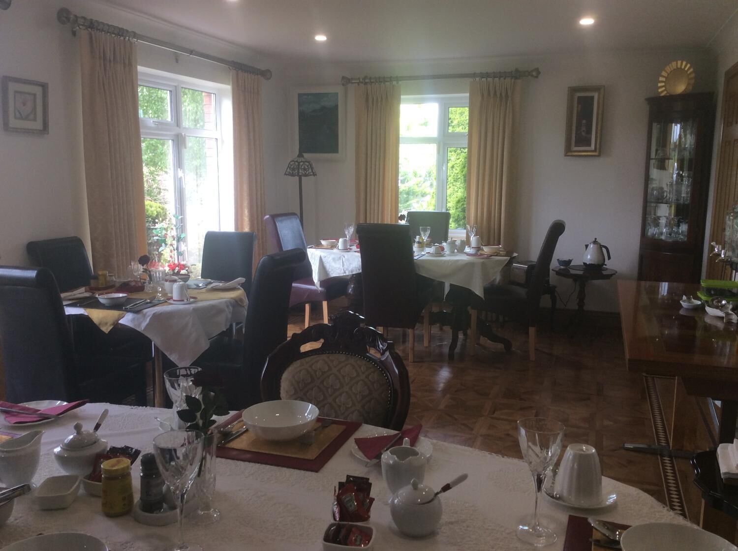 A dining area with multiple tables set for meals, chairs, and a variety of tableware.