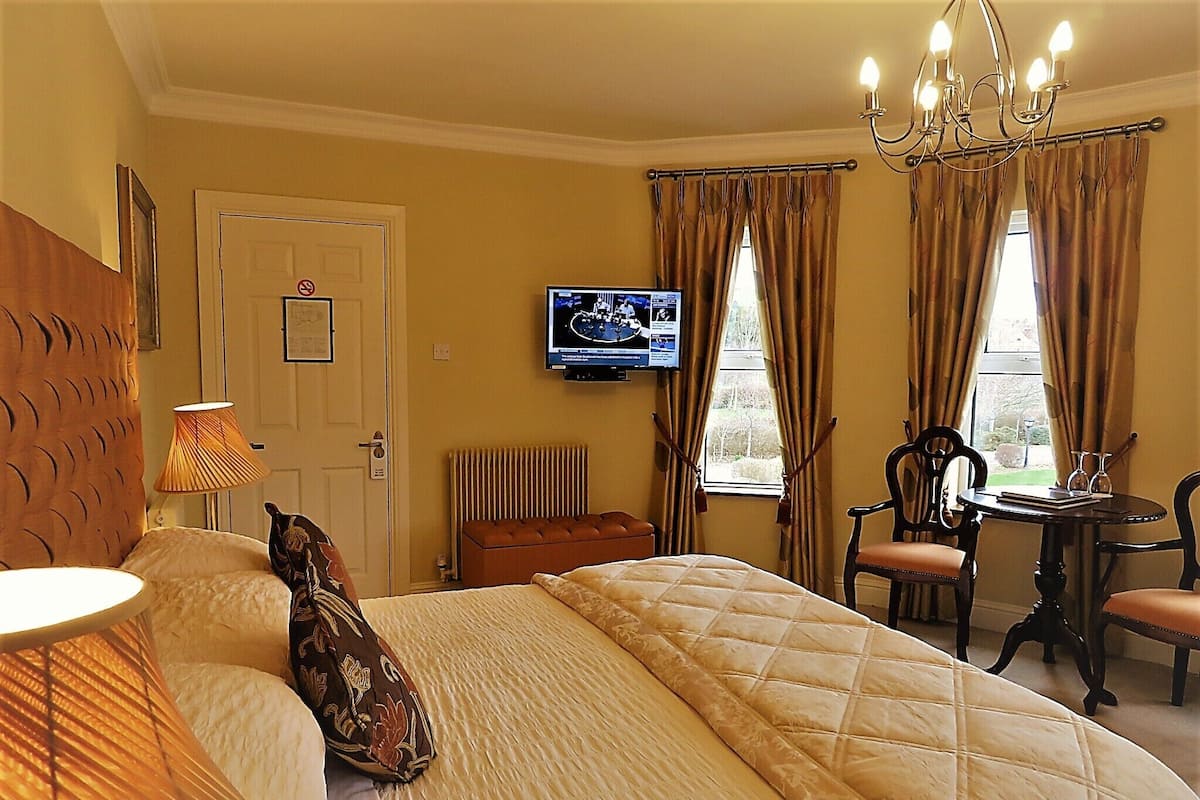 A hotel room with a bed, a desk, a chair, a television, and a window with curtains.