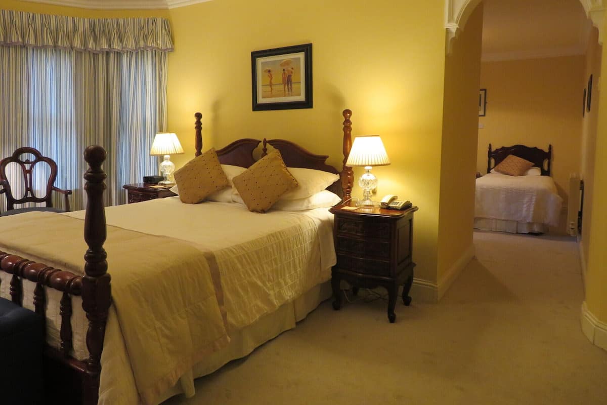 A hotel room with a large bed, two bedside tables, a lamp, a framed picture on the wall, and a chair.