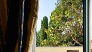 A room with a sliding glass door leading to an outdoor patio. The patio has a tiled floor and includes a small table with a plant and two chairs. - Hotel Ristorante La Piana (Amorosi)