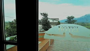 A hotel sign with a swan and the word "HOTEL" in the foreground, with a view of a building and mountains in the background. - Hotel Ristorante La Piana (Amorosi)