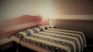 Una cama individual con una colcha estampada y un cabecero, una mesita de noche y una pared con papel tapiz decorado.