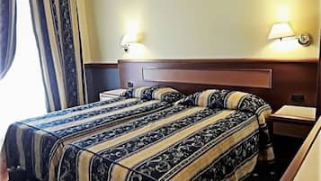 A hotel room with a double bed, two bedside tables, and two wall-mounted lamps.