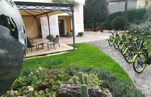 A courtyard with a covered seating area, a row of bicycles, and a garden with cacti and other plants.
