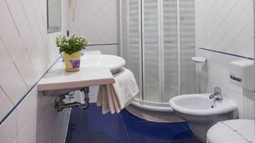 Ein modernes Badezimmer mit einer Duschkabine aus Glas, einem Waschbecken, einem Bidet und einer Toilette.