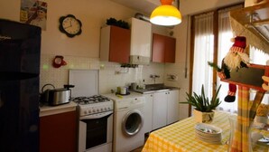 A compact kitchen with a gas stove, washing machine, and a clock on the wall. - Bed and Breakfast La Casa Di Elide (Arezzo)