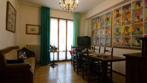 A dining area with a table and chairs, a chandelier, a television, and a wall with colorful artwork. - Bed and Breakfast La Casa Di Elide (Arezzo)
