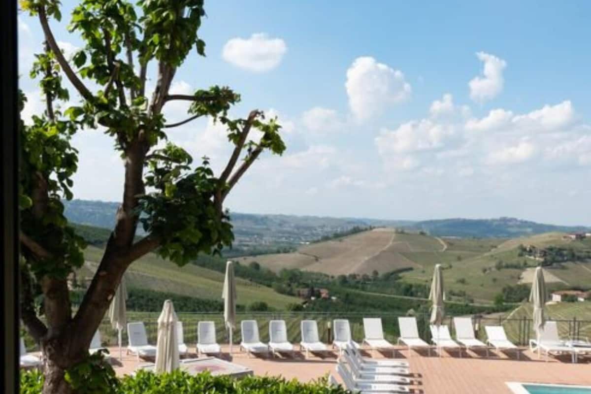 A poolside area with lounge chairs and umbrellas, overlooking a hilly landscape.