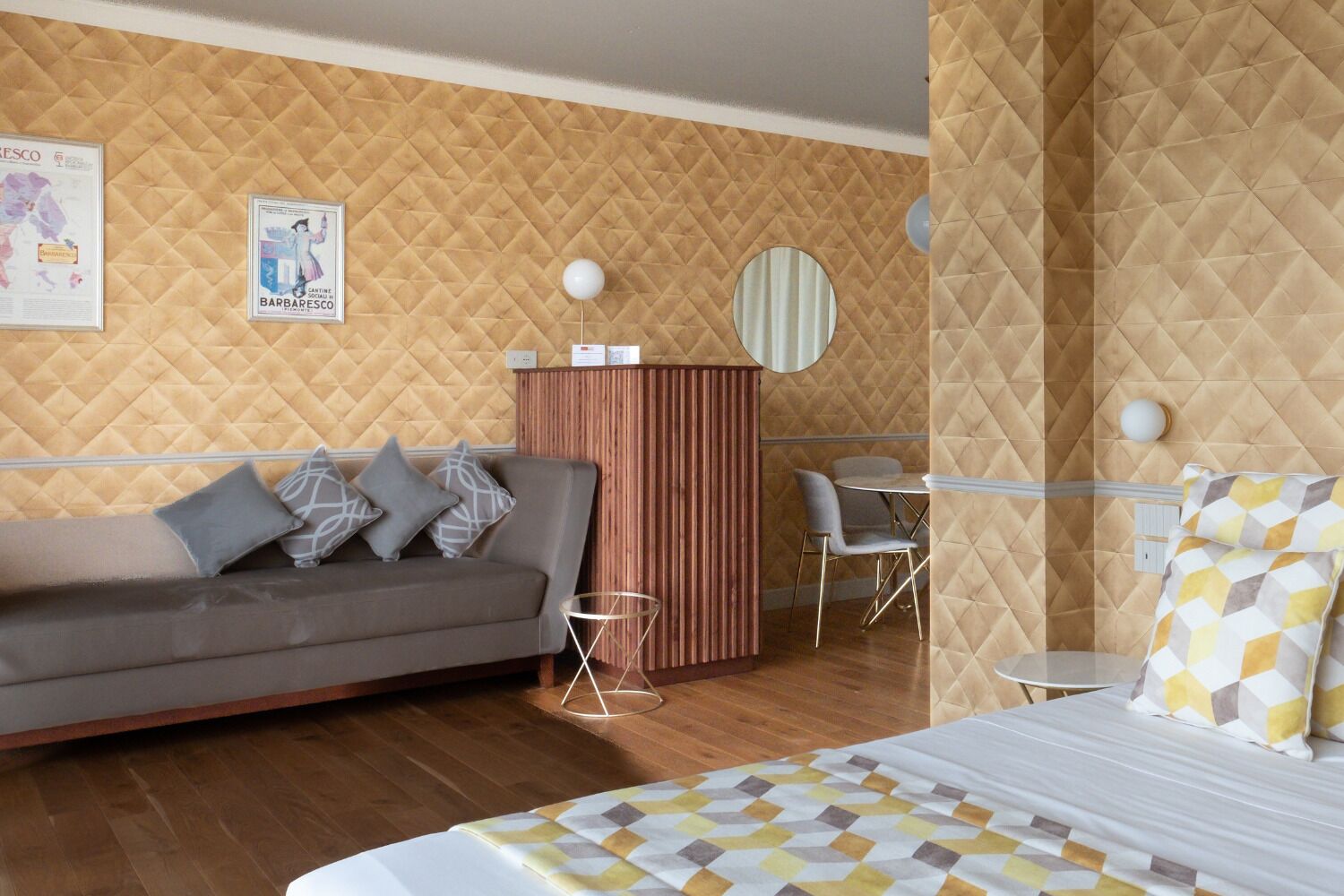 A modern hotel room with a sofa, a bed, a desk, and a chair.