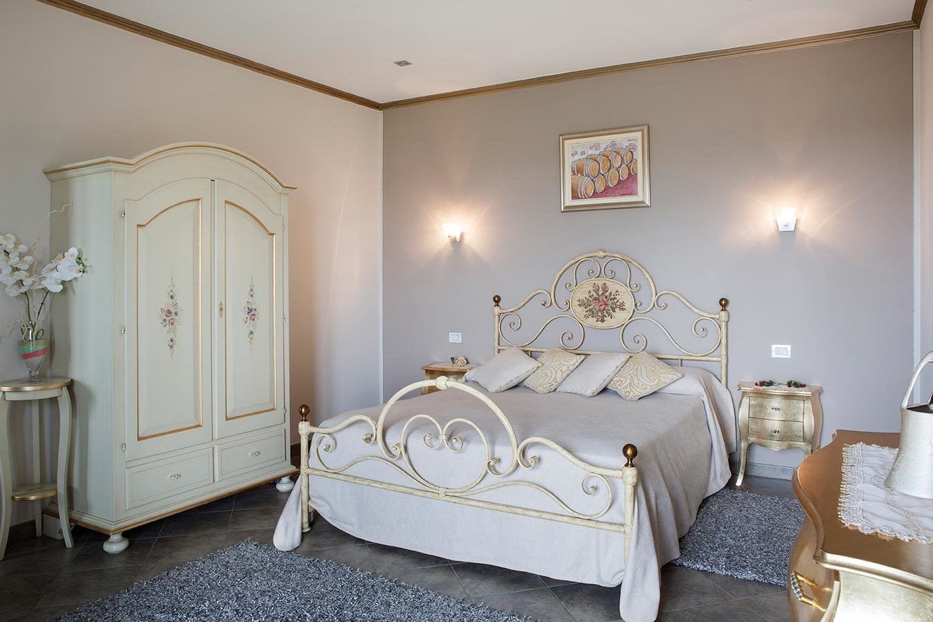 A bedroom with a bed, a wardrobe, a nightstand, and a wall-mounted light fixture.
