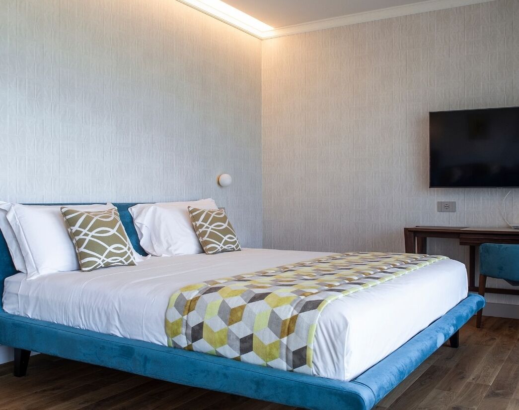 Una habitación de hotel con una cama, un escritorio y un televisor montado en la pared.