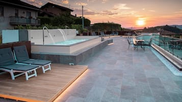Terrassa al terrat amb banyera d'hidromassatge, seients de relaxació i mobiliari exterior.