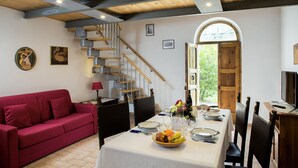 A dining area with a staircase, a red sofa, and a table set for a meal. - All'Antica Mattonata (Assisi)