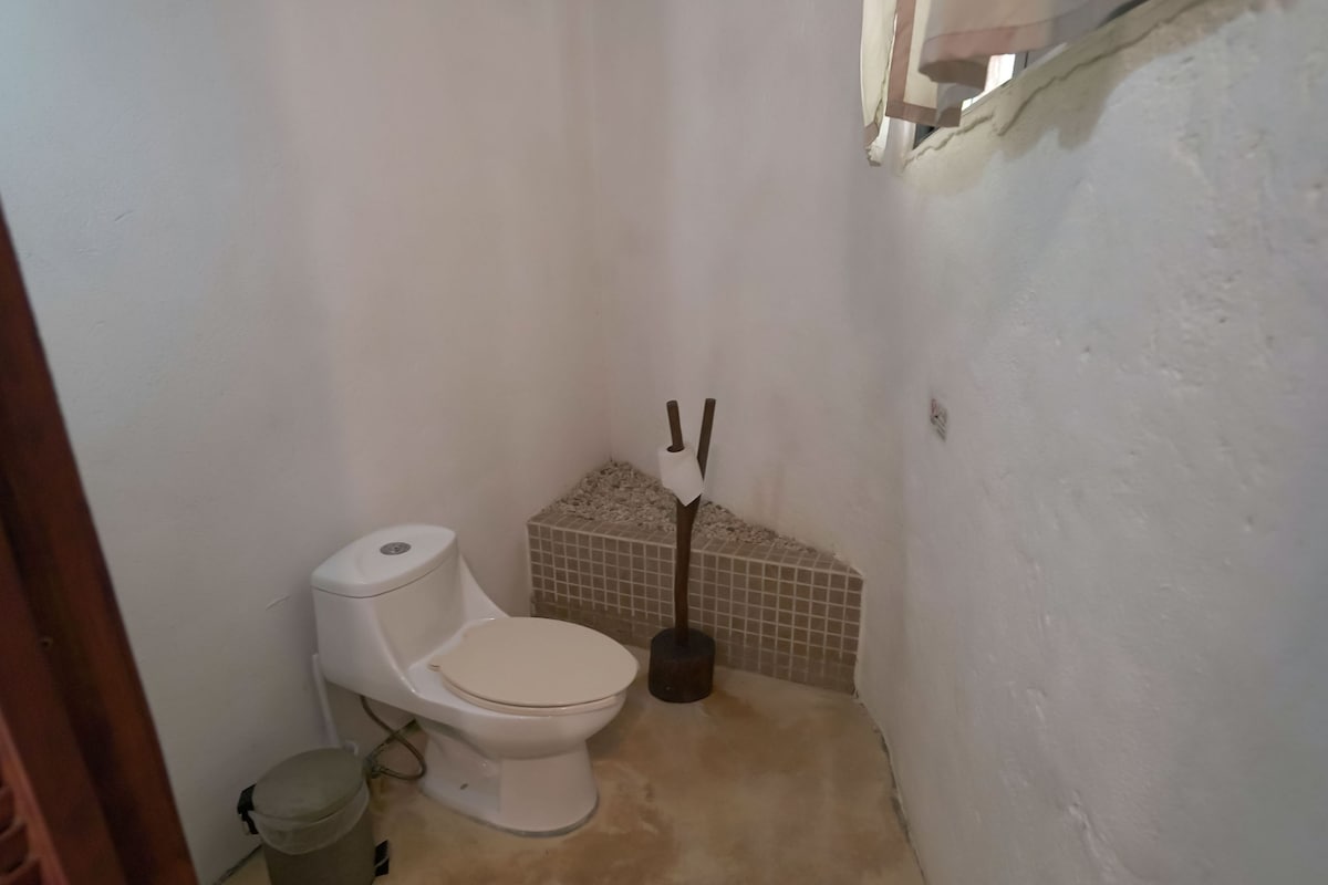 Une petite salle de bain simple, avec des toilettes, une poubelle et un coin carrelé.