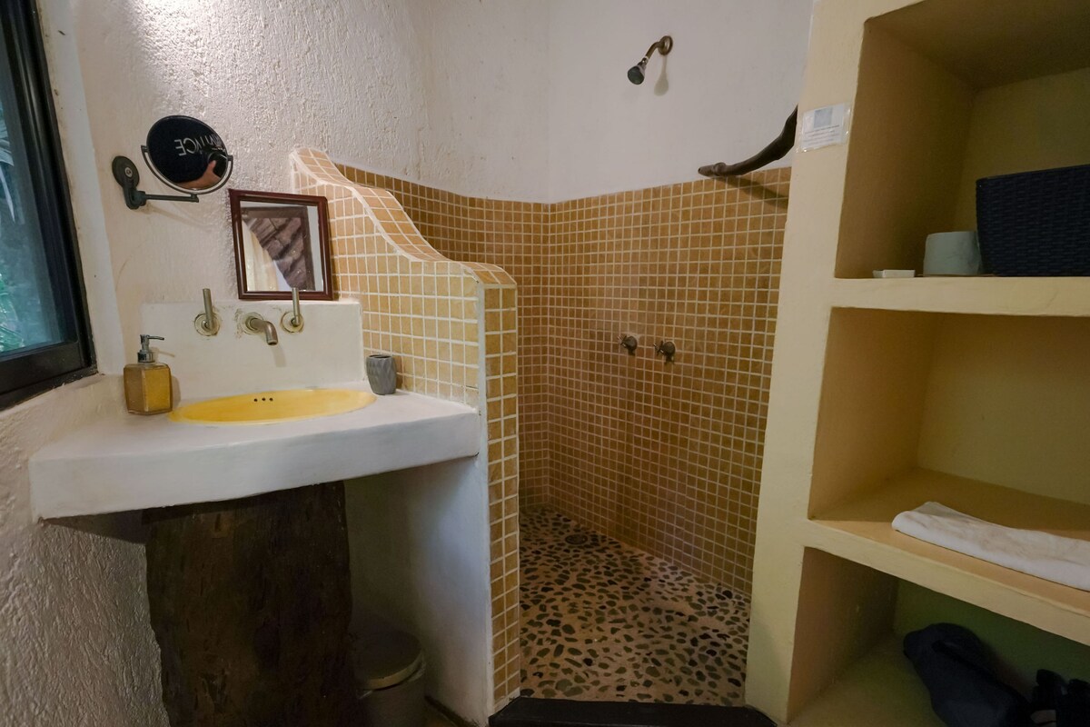 A bathroom with a sink, mirror, shower, and shelves.