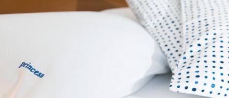 A bed with a white pillow and a blue polka-dotted pillowcase.