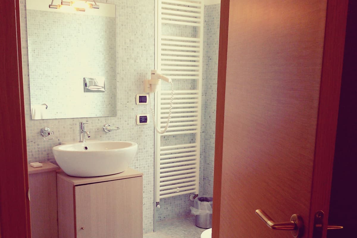 A bathroom with a sink, mirror, and towel rack.