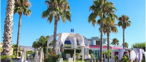 Un resort con piscina, palmeras y un pabellón techado.