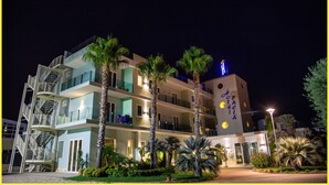 A multi-story hotel with a modern design, featuring balconies, a visible staircase, and a well-lit entrance. - Grand Hotel Paclà (Avola)