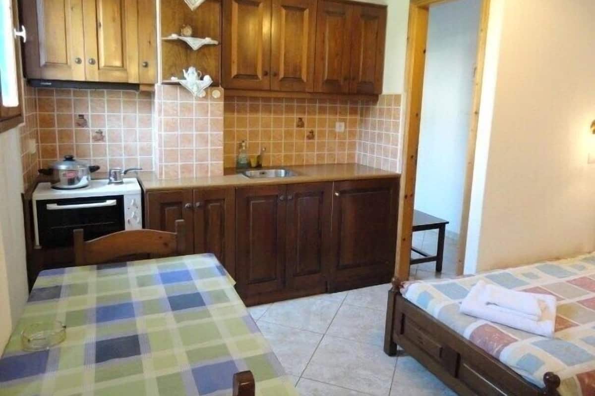 Una habitación pequeña y funcional con kitchenette, dos camas individuales y un armario de madera.