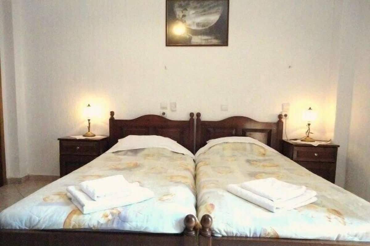 Cama doble con colcha estampada y dos mesitas de noche con lámparas.