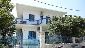 Un edificio de dos pisos con fachada blanca y balcones azules. Dos motocicletas estacionadas adelante.